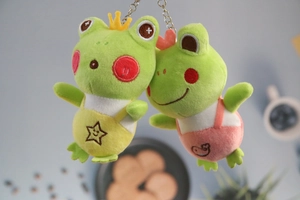 Detail of plush frog keychains with cute crowns and colorful embroidered overalls