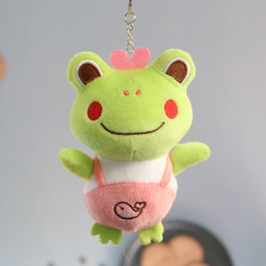 Detail of green frog plush keychain with pink heart decoration and whale overall
