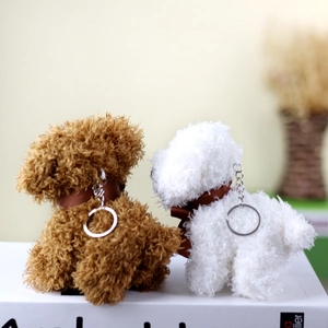 Detail of plush teddy dog charms in brown and white with silk bows and metal keychains