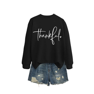 Women's black thankful sweatshirt paired with distressed blue denim shorts on white background
