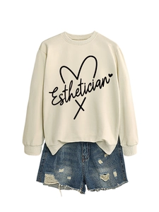 Flat lay of apricot Esthetician sweatshirt with blue ripped denim shorts on white background