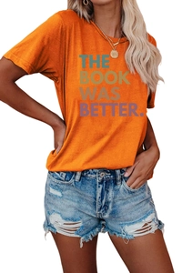Detalle de camiseta de algodón naranja con la inscripción 'THE BOOK WAS BETTER' impresa