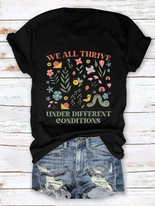 Flat lay of black T-shirt with nature graphic and denim shorts on white wood