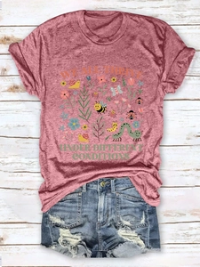 Flat lay of a mauve t-shirt with 'We All Thrive' floral print and distressed denim shorts