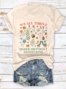 Flat lay of cream T-shirt with nature illustration and distressed denim shorts on wood