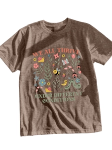 Close-up of 'WE ALL THRIVE UNDER DIFFERENT CONDITIONS' print on brown cotton T-shirt