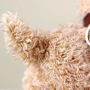 Close-up of soft curly plush fur texture on a teddy dog toy with a silver metal keyring