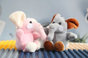 Gros plan de porte-clés éléphants en peluche rose et gris en tissu doux avec yeux ronds