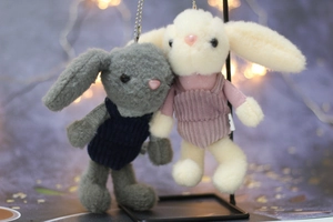 Close-up of cute plush bunny keychains in corduroy overalls with a soft bokeh background
