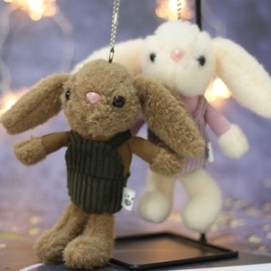 Close-up of cute plush bunny keychains in green overalls and pink shirts with metal chains