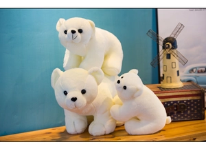 Three soft plush polar bears of different sizes on a wooden desk with a bright background