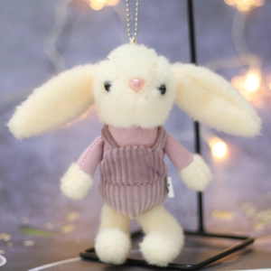 Cute cream plush bunny keychain in pink corduroy overalls hanging on a metal stand