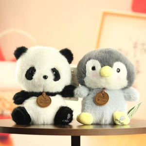 Close-up of cute plush panda and penguin dolls with leather tags on a wooden table