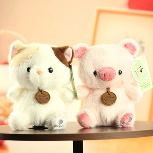 Close-up of cute plush cat and pig dolls with wooden tags on a wooden table