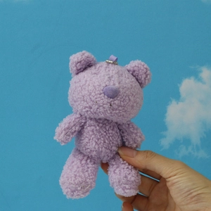 Close-up of a soft purple teddy bear plush keychain with curly fleece texture