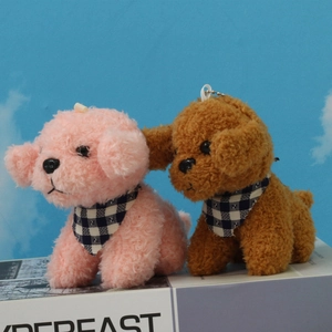 Plush teddy dog keychains in pink and brown with checkered scarves on a book