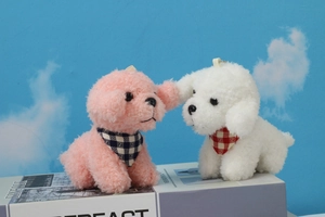 Detail of pink and white plush poodle keychains with checkered scarves on a blue background