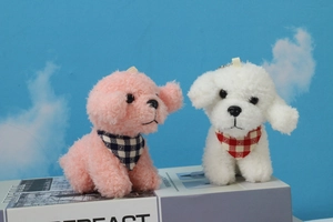 Detail of pink and white plush teddy dog keychains with checkered scarves on books