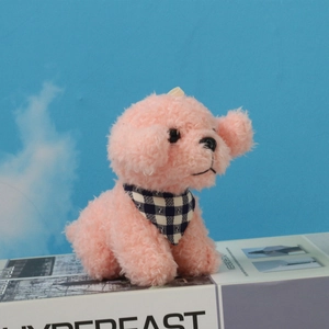 Close-up of pink curly plush teddy dog wearing a blue checkered scarf on a gift box
