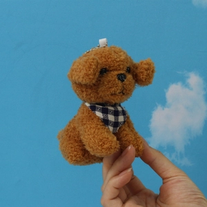 Detailed close-up of a brown plush teddy dog keychain with a blue plaid bandana