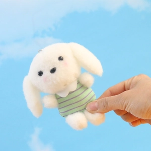 Detailopname van een witte pluche puppy sleutelhanger met een gestreept shirt