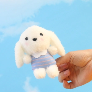 Close-up van zachte witte pluche honden sleutelhanger met blauw-roze vest