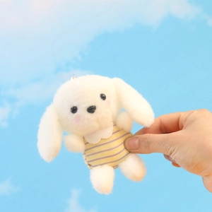 Detail van een pluche witte puppy sleutelhanger met een geel en paars gestreept pakje