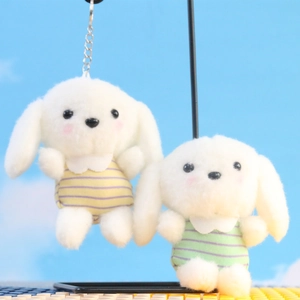 Detailopname van twee pluche witte honden sleutelhangers met gekleurde shirtjes op
