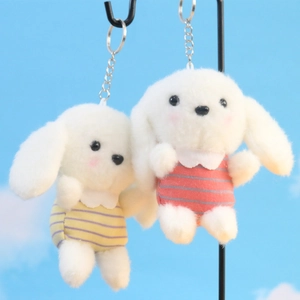 Detailopname van witte hondenknuffel hangers met gestreepte truien tegen een blauwe lucht