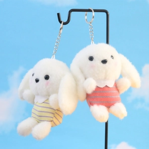 Detailopname van witte pluche honden-sleutelhangers met gestreepte kleding