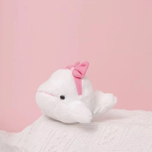 Nahaufnahme von weißem Beluga-Plüschtier mit rosa Schleife auf Strickunterlage