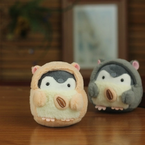 Cute penguin plush charm with hamster hood and sunflower seed on a wooden desk