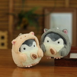 Close-up of cute plush penguin keychains holding sunflower seeds on wooden surface
