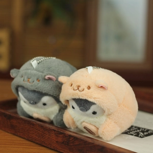Detail view of plush penguin pendants in grey and orange animal hoodies with bead chains