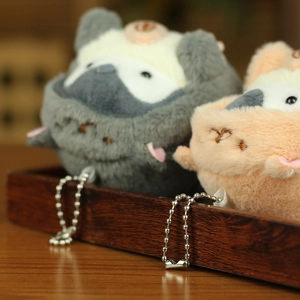 Close-up of cute plush penguin pendants in grey and orange on a wooden tray