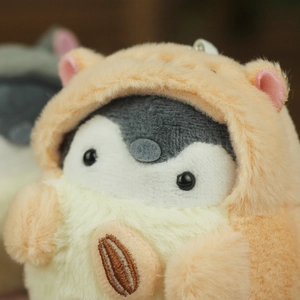 Close-up of plush penguin keychain with orange hat and embroidered sunflower seed
