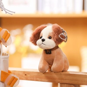 Close-up of cute plush dog keychain with brown leather collar and metal lobster clasp