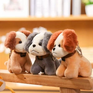 Three cute plush dog keychains in brown, grey and orange colors on wood desk