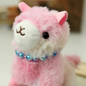Close-up of pink alpaca plush with soft faux fur and elegant pearl necklace detail