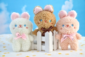 Dettaglio di ciondoli a forma di coniglietto in peluche bianco, marrone e rosa