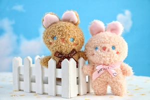 Vista ravvicinata di coniglietti di peluche con nastri Love su staccionata bianca