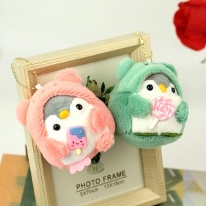 Close-up of cute penguin plush keychains in pink and green hoodies with accessories