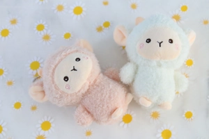 Dettaglio di portachiavi a forma di pecora rosa e verde in peluche con clip metallica