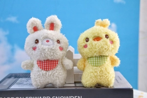 Detailed close-up of plush rabbit and chick toys with checkered bibs on blue background