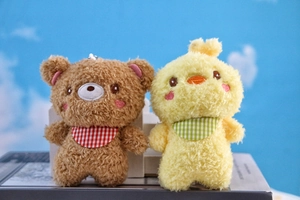 Detailed view of plush bear and chick charms with checkered scarves on books