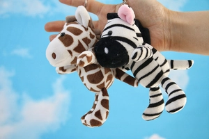Detail of plush giraffe and zebra keychains with metal clasps held in hand
