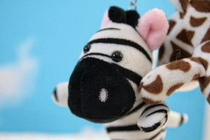 Close-up of zebra plush keychain with black and white stripes and soft pink ear details