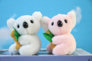 Dettaglio di portachiavi koala in peluche bianco e rosa seduti su un libro