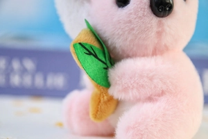 Dettaglio ravvicinato di un koala rosa di peluche con foglia verde e pelo soffice