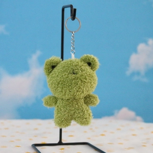 Close-up of green plush frog keychain with curly fur texture and silver metal clip